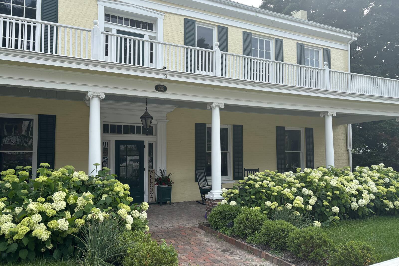 A historic Weston, Missouri home on a summer morning, hydrangeas in bloom along the front walk